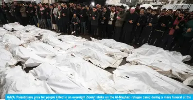  ?? — AFP ?? GAZA: Palestinia­ns pray for people killed in an overnight Zionist strike on the Al-Maghazi refugee camp during a mass funeral at the Al-Aqsa hospital in Deir Al-Balah in the southern Gaza Strip on Dec 25, 2023.