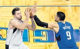  ?? JOHN RAOUX/AP ?? Mavericks guard Luka Doncic moves to get past Magic center Nikola Vucevic (9) during the first half on Monday night.