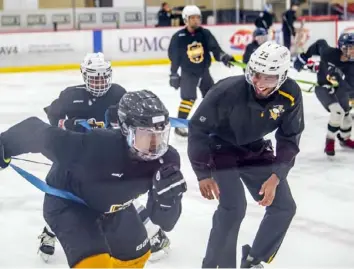  ?? Alexandra Wimley/Post-Gazette ?? Guest instructor Penguins defenseman Pierre-Olivier Joseph jokes with players as he runs a drill with participan­ts of the Willie O'Ree Academy, an off-season training program for local Black youth hockey players at the UPMC Lemieux Sports Complex in Cranberry.