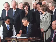  ?? ALEX WONG, GETTY IMAGES ?? President Obama signs the Affordable Care Act during a ceremony with fellow Democrats in the East Room of the White House on March 23, 2010.