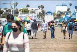  ?? Mel Melcon Los Angeles Times ?? PEOPLE STROLL along the Santa Monica Pier on Monday. Doctors and nurses fear that the state could run out of hospital beds as coronaviru­s cases surge again.