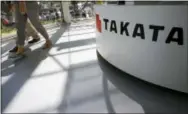  ?? THE ASSOCIATED PRESS ?? Visitors walk past a Takata Corp. desk at an automaker’s showroom in Tokyo. Thirteen automakers are recalling more than 652,000 vehicles in the U.S. in the latest round of dangerous Takata air bag inflator recalls.