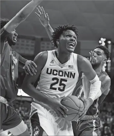  ?? JESSICA HILL/AP PHOTO ?? UConn’s Josh Carlton, center, is guarded by Morehead State’s James Baker, left, and Lamontray Harris, right, during the second half of Thursday’s game at Gampel Pavilion in Storrs.