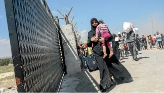  ?? GETTY IMAGES ?? A Syrian refugee and her child walk towards the border gate at the Oncupinar crossing in the town of Kills in Turkey.