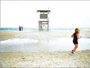  ??  ?? A jogger runs past a lifeguard stand as Hurricane Florence approaches on Tuesday in Wrightsvil­le Beach, North Carolina.