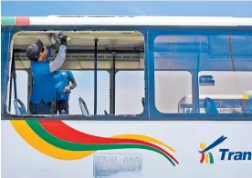  ?? JOSEFINA VILLARREAL ?? Dos hombres cambian los vidrios de un bus de Transmetro apedreado.