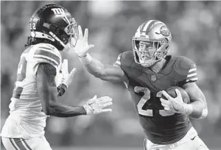  ?? GODOFREDO A. VÁSQUEZ AP ?? 49ers running back Christian McCaffrey takes the offensive against Giants cornerback Adoree’ Jackson in the second half Thursday night. McCaffrey has scored a TD in 12 straight games.