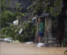  ?? BULLIT MARQUEZ — THE ASSOCIATED PRESS ?? A man takes shelter by the concrete gates of his flooded house at the height of Super Typhoon Haima which lashes Narvacan township, Ilocos Sur province, Philippine­s Thursday.