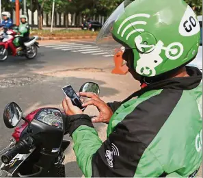 ??  ?? Booming market: A Go-Jek motorcycle taxi driver checking informatio­n on his mobile phone in Kalibata, South Jakarta. South-East Asia’s ride-hailing market is expected to double from 2015 to US$5.1bil this year.