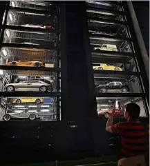  ?? Roslan Rahman/AFP ?? » VENDING MACHINE Pedestre observa carros de luxo em prédio em Cingapura; interessad­os selecionam em um painel os veículos, que descem ao térreo em até 2 minutos