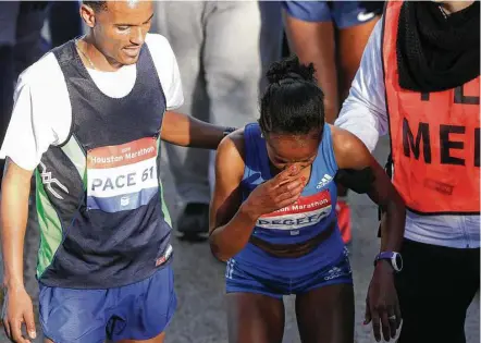  ?? Yi-Chin Lee / Houston Chronicle ?? Ethiopian runner Biruktayit Degefa, center, is helped by her husband Abinet Adraro, left, and a medic after winning the women’s race in Sunday’s Chevron Houston Marathon.