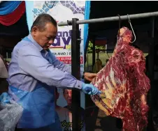  ?? ?? Aminuddin carves the meat as the gimmick to launch the Mantai Rayo 2024 programme. — Bernama photo