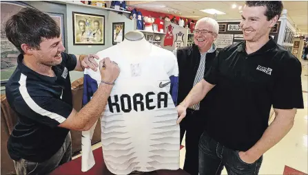  ?? CLIFFORD SKARSTEDT EXAMINER ?? Doug Gibson with South Korea Winter Olympics players Michael Swift, left, and Bryan Young sign a hockey jersey Tuesday that will be up for auction.