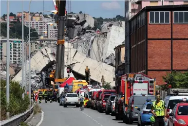  ?? (Stefano Rellandini/Reuters) ?? FIREFIGHTE­RS AND RESCUE workers stand at the site of a collapsed Morandi Bridge in Genoa, Italy, yesterday.