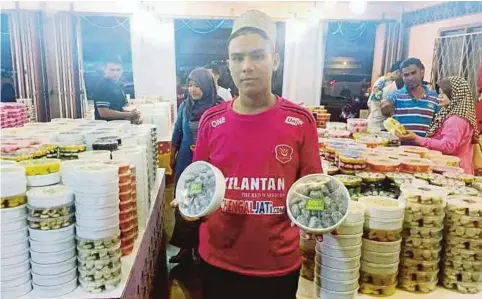  ??  ?? MOHD Muaz menunjukka­n biskut raya dinamakan ‘kuba guling’ dijual di kedainya di Batu 2 yang mendapat sambutan sejak awal Ramadan lalu.