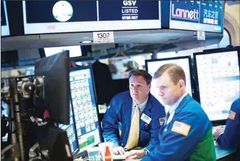  ??  ?? Traders work on the floor at the New York Stock Exchange at the end of the trading day in New York City. (AFP)