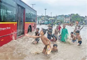  ?? PTI ?? Children splash water on a DTC bus after monsoon rainfall in New Delhi on Saturday. —