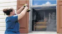  ?? TAIMY ALVAREZ/STAFF PHOTOGRAPH­ER ?? Nadia Meinero puts up shutters on her mobile home as her son, Anthony, looks from inside Thursday.