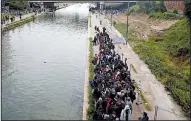  ?? AP/THIBAULT CAMUS ?? Refugees line up as they evacuate a makeshift camp Wednesday in Paris.