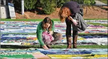  ?? HYOSUB SHIN / HSHIN@AJC.COM ?? Kate Ogorzaly (left) touched one of the AIDS Memorial Quilt displays as Ogorzaly and Meg Bertram, then both graduate students majoring in Global Health, stop for a look at the AIDS Memorial Quilt at Emory University’s McDonough Field.