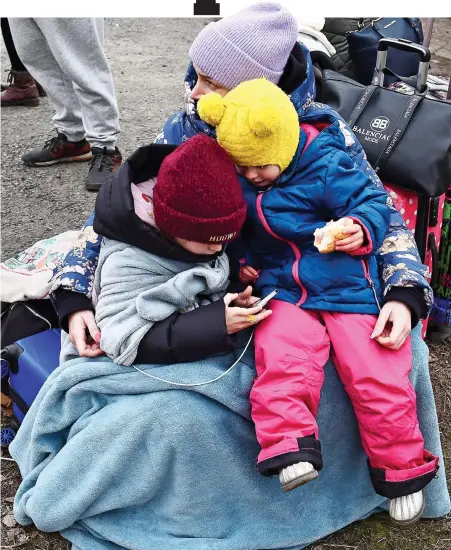  ?? ?? WE MADE IT: A woman and two children rest amid their meagre possession­s after an arduous journey to Hungary