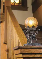  ??  ?? LEFT The five-globe chandelier in the stair hall, a prized survivor, is original to the house. The stair is located at the center of the house. BELOW The fanciful bronze and glass fixture on the newel post was a compatible find discovered at an antiques shop.