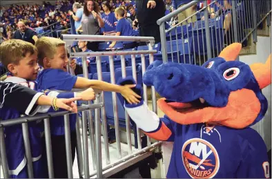  ?? Christian Abraham / Hearst Connecticu­t Media ?? A couple of young New York Islanders fans greet mascot Sparky the Dragon prior to an NHL exhibition hockey game between the New York Islanders and the New York Rangers at the Webster Bank Arena in Bridgeport in 2017. The Islanders’ AHL affiliate team, formerly known as the Sound Tigers, will return to the arena this year as the Bridgeport Islanders.