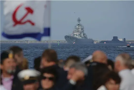  ?? (Anton Vaganov/Reuters) ?? RUSSIANS GATHER last year to watch the Navy Day parade, with the nuclear missile cruiser Pyotr Veliky (Peter the Great) and nuclear submarine Dmitry Donskoy seen in the background near St. Petersburg. In the wild and complex mind-games of nuclear...