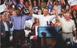  ?? Bloomberg ?? Former US President Barack Obama, Andrew Gillum (left), Democratic candidate for governor of Florida, and Senator Bill Nelson (right), a Democrat from Florida, raise their arms during a campaign rally for Florida’s Democratic candidates in Miami on Friday.