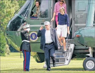  ?? AP PHOTO ?? President Donald Trump, center, returns a salute as he steps off Marine One helicopter with first lady Melania Trump and their son Barron Trump, 11, on the South Lawn of the White House in Washington, Sunday.