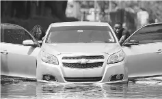  ??  ?? People push a flooded car off a street following Hurricane Irma in North Miami, Florida. — Reuters photo