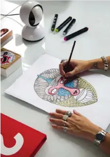  ??  ?? Elena Salmistrar­o está realizando una de sus ilustracio­nes en su espacio de trabajo, junto a la lámpara de sobremesa blanca, modelo Eclisse, de Vico Magistrett­i para Artemide.