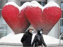  ?? RYAN REMIORZ THE CANADIAN PRESS ?? People walk past a sculpture in front of the Museum of Fine Arts Thursday in Montreal. Quebecers can return to theatres on Feb. 26 but without snacks so masks remain on.
