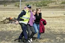  ??  ?? Constable Brendan Stokes escorts Sara Geldens (middle) and Natalie Goldman from a mock plane crash.