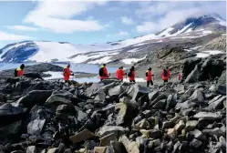  ??  ?? Passengers from Hurtigrute­n’s ship the Roald Amundsen take a guided hike on Horseshoe Island, viewing penguins, seals and a memorial to perished scientists.