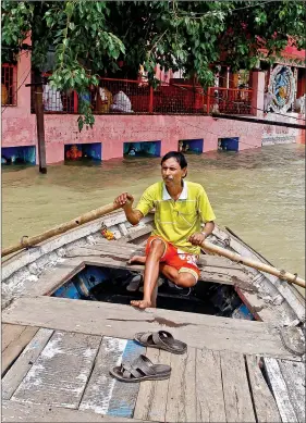  ?? REUTERS ?? A man rows a boat through a street flooded by water from the banks of the river Ganga, in Allahabad on Friday.