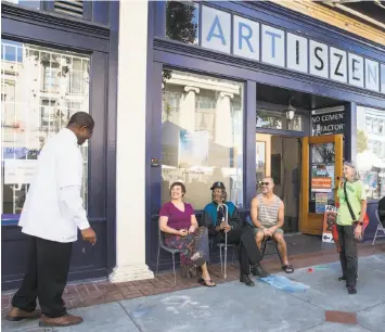  ??  ?? Dominique Gutierrez, Charles Barnes and Sean Gutierrez, seated left to right, talk with with friends while seated outside the Artiszen Cultural Arts Center in Vallejo. The co-op offers space for rent and a 1,600-square-foot gallery for shows, workshops...