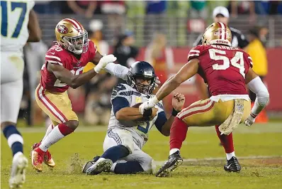  ?? AP Photo/Tony Avelar ?? ■ Seattle Seahawks quarterbac­k Russell Wilson (3) slides between San Francisco 49ers free safety Jimmie Ward (20) and middle linebacker Fred Warner (54) during an NFL football game Monday in Santa Clara, Calif.