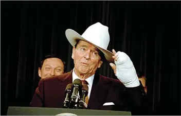  ?? DOUG MILLS / AP / FILE ?? President Ronald Reagan, using his bandaged hand, tips his white cowboy hat which was presented to him by the trade organizati­on he was speaking to in Washington, D.C., on Jan. 9, 1989. Reagan had undergone surgery to correct a curvature in the ring finger of his left hand.