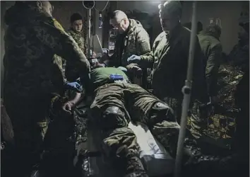  ?? Yevhen Titov Associated Press ?? MEDICS tend to a wounded Ukrainian soldier near Bakhmut, a city of salt and gypsum mines that has endured a months-long offensive by Russia. The battle for the city has become a symbol of Ukrainian resistance.