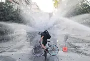  ?? REUTERS ?? A man on a bicycle is sprayed by a water cannon during a protest against Chile’s government in Santiago.