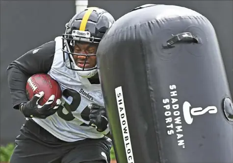  ?? Peter Diana/Post-Gazette ?? A HARD KNOCK No one is hitting back, but running back Malik Williams finds that taking on a tackling dummy during drills Wednesday at the Steelers South Side facility can test a body.