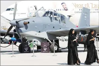  ?? (AFP) ?? Women walk past a US-made Archangel S2R-660 displayed during the Dubai Airshow on Nov 14 in the
United Arab Emirates.