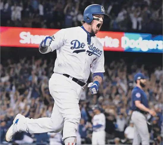  ?? Wally Skalij Los Angeles Times ?? DODGERS CATCHER Yasmani Grandal lets out a roar to rival that of the Dodger Stadium crowd after hitting a two-run homer off Jake Arrieta, right, in the fourth.