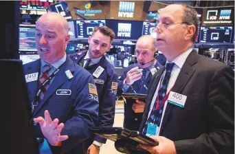  ?? Bloomberg ?? Traders at the New York Stock Exchange on Friday. US equity indexes fluctuated as energy and utility gains were offset by plunging retail and technology stocks.