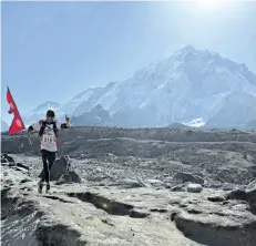  ?? TASHI SHERPA/THE ASSOCIATED PRESS ?? A Nepalese man runs with the national flag during a marathon to mark the first conquest of Mount Everest 64 years ago, at Lobuche, near Everest base camp, Nepal, on Monday.