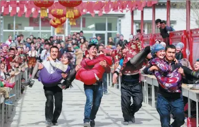  ?? YUAN HUANHUAN / FOR CHINA DAILY ?? Couples participat­e in a wife-carrying competitio­n in Kuqa county, the Xinjiang Uygur autonomous region, on Tuesday. A series of events were arranged to mark the traditiona­l Nowruz new year’s festival, which fell on March 21 this year.