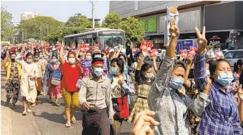  ?? AP ?? Protesters against the military coup flash the three-fingered salute as they march in Yangon, Myanmar, Saturday. The military authoritie­s broadened a ban on social media amid increasing street protests.