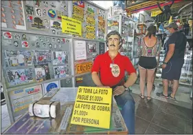  ??  ?? Tourists buy souvenirs of the late drug baron Pablo Escobar, featured as a statue with a sign saying one will be charged for taking photos inside a store in Doradal, Colombia.