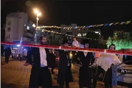  ?? MAYA ALLERUZZO — THE ASSOCIATED PRESS ?? Ultra-Orthodox Jews stand behind police tape after a stabbing attack in the town of Elad, Israel, Thursday. Israeli medics say at least three people were killed in a stabbing attack near Tel Aviv on Thursday night. Israeli police said they suspect it was a militant attack.